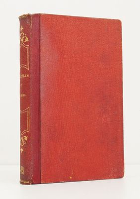 un vieux livre rouge avec des bordures dorées posé sur une surface blanche