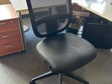 a black office chair sitting in front of a computer desk