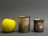 three cups and an apple next to each other