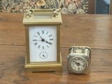 a small clock sitting next to a small clock on a table