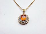 a gold necklace with an orange stone surrounded by diamonds