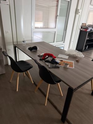 une table avec des chaises et un vase posé dessus, dans une pièce