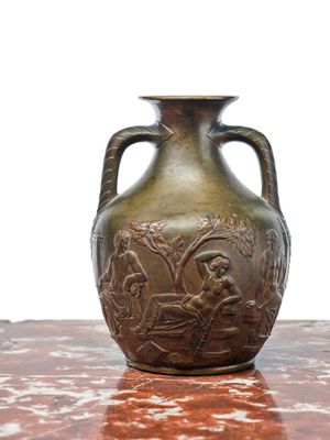 un vase en bronze posé sur une table, sur fond blanc