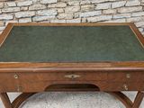 an old wooden desk with a green top on a stone floor