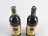 two bottles of wine sitting next to each other on a white surface