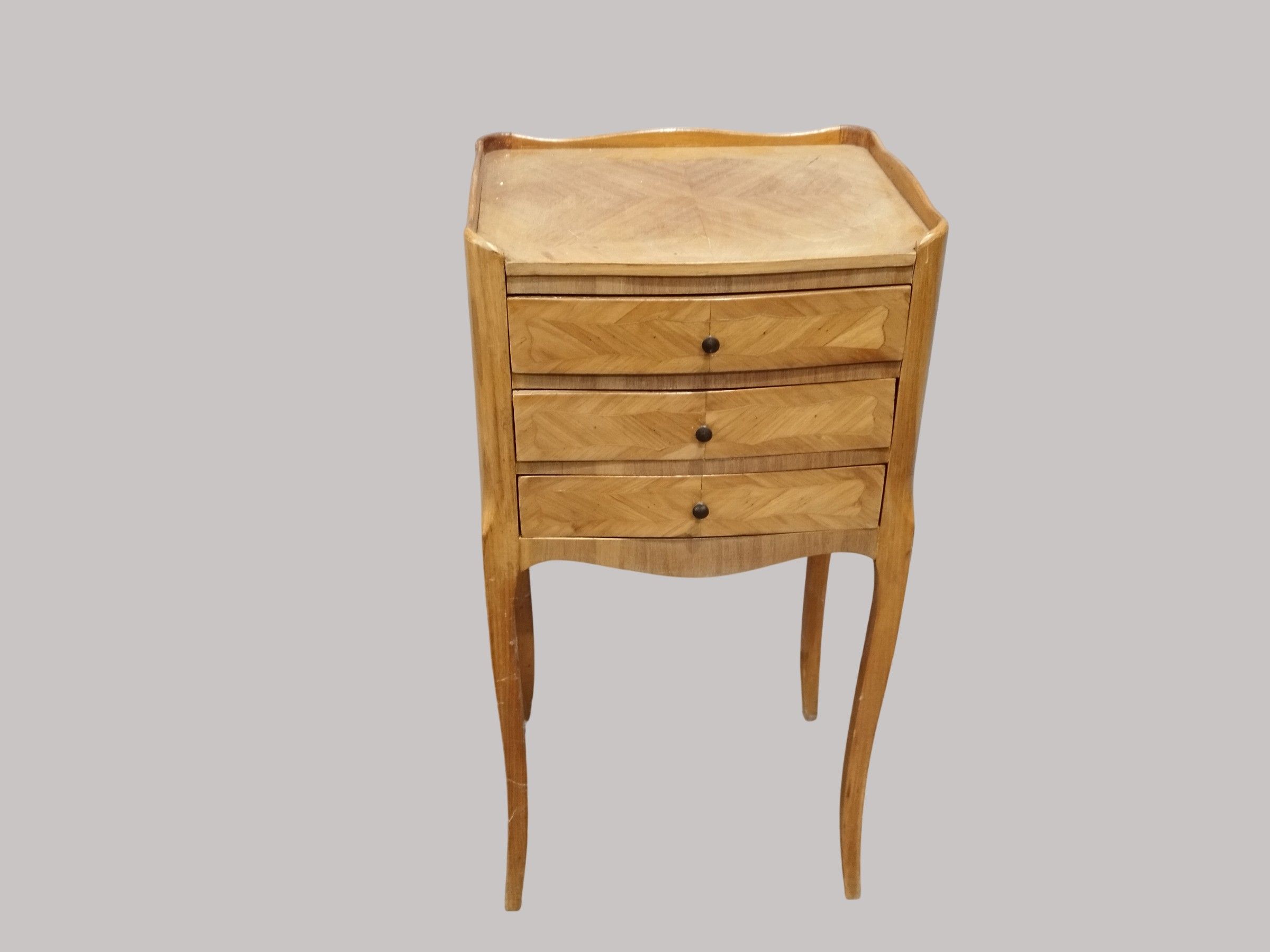Une table de chevet en bois de placage ouvrant par trois tir…