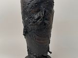 un vase noir orné d'un visage sur un fond blanc
