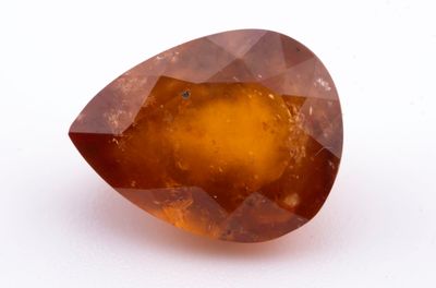 un gros plan d'un gros diamant orange sur une surface blanche