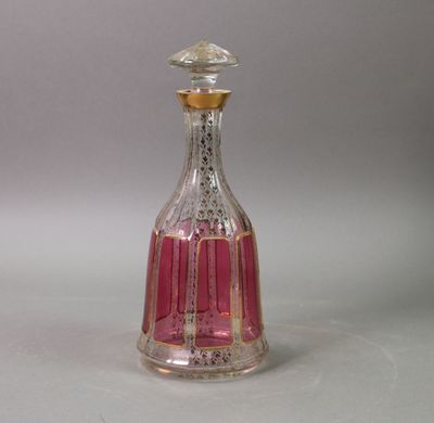 a pink glass bottle with a gold top on a white surface