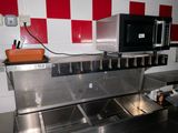 une cuisine équipée d'un évier et d'un micro-ondes posé sur le plan de travail