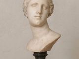 marble bust of a woman with curly hair on a marble base
