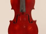 an old violin hanging from a string on a white wall