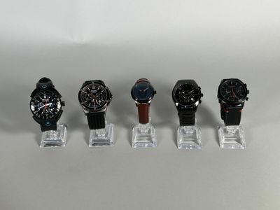 several watches are lined up in a row on a clear stand