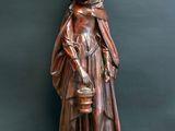 a wooden statue of a woman holding a bucket and a dog