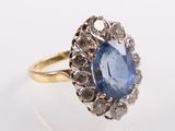 a close up of a blue sapphire and diamond ring on a white surface
