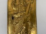 une plaque plaquée or représentant une femme tenant une croix