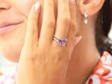 quelqu'un enfile à son doigt une bague sertie d'une pierre violette