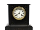 une horloge noire et dorée avec des chiffres romains