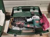 une boîte à outils verte posée par terre, contenant des outils