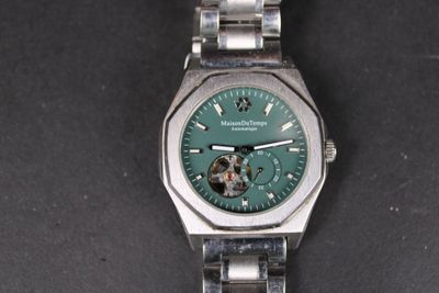 une montre en argent avec un cadran vert sur un fond noir