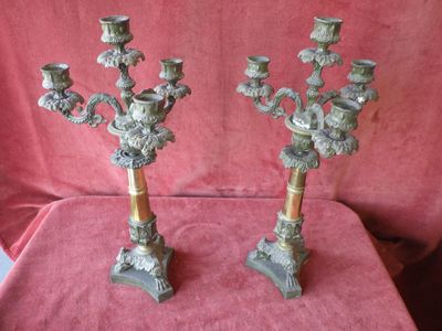 pair of antique brass candelabs on a red cloth