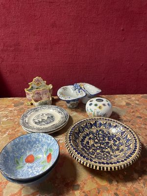 many plates and bowls sitting on a table with a red wall in the background