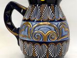 un vase bleu et or muni d'une anse noire