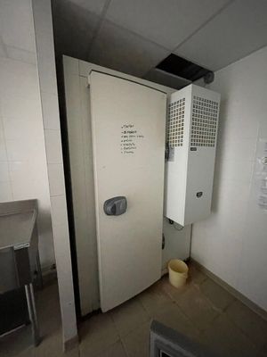un réfrigérateur blanc dans un coin d'une pièce, avec une poubelle à l'intérieur