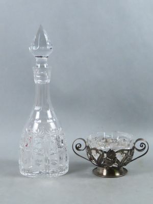 a glass decanter next to a glass bowl on a table