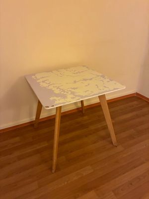 une petite table blanche aux pieds en bois dans une pièce