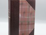 un livre marron à la couverture à carreaux posé sur une table