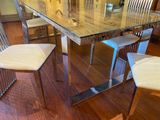 a glass table with four chairs and a vase on top of it