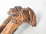 a close up of a wooden walking stick with a dog on it