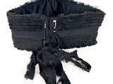 un corset noir muni d'une fermeture éclair, posé sur un fond blanc