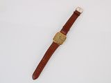 a brown watch with a gold face and brown leather strap