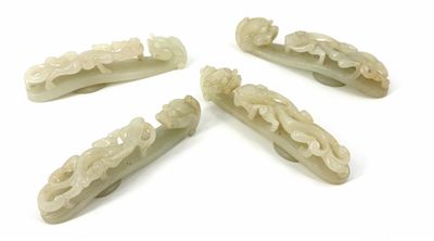 four pieces of carved jade hair clips on a white surface