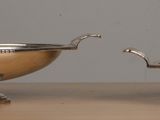 two silver bowls sitting on a table next to each other