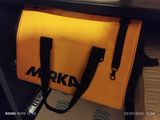 un ordinateur portable posé sur un bureau, sur lequel se trouve un sac jaune