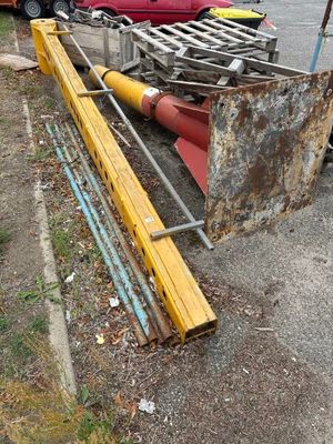une voiture rouge garée sur un parking, à côté d'un tas de ferraille