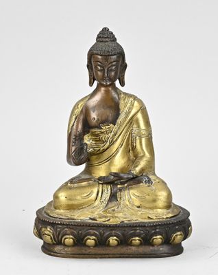 une statue en bronze représentant un Bouddha assis sur un socle en forme de lotus