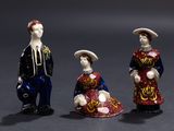 three figurines of a man and a woman dressed in traditional clothing
