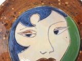 painting of a woman ' s face on a plate with a green border