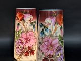 deux vases sur lesquels sont peints des fleurs sur un fond noir