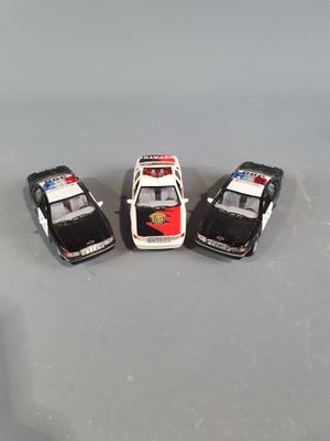three toy police cars are lined up in a row on a gray surface