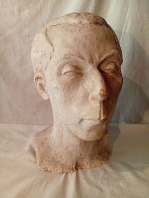 une sculpture en argile représentant une tête d'homme posée sur un tissu blanc
