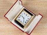 a small clock in a red box on a wooden table