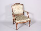 une chaise dont le dossier est recouvert d'un tissu à motifs floraux et dont la structure est en bois