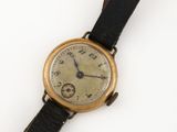 une vieille montre-bracelet avec un bracelet en cuir noir et un cadran doré
