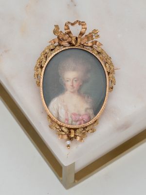 portrait of a woman in a white dress with a gold frame on a marble surface