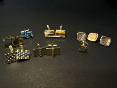 five pairs of cufflinks and two cufflinks on a table